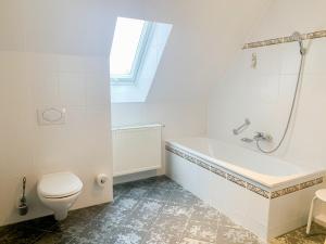 a white bathroom with a tub and a toilet at Landhotel Bauernschmitt in Pottenstein +57 photos
