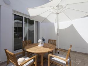 a wooden table and chairs with an umbrella at La Fontanilla Place in Conil de la Frontera
