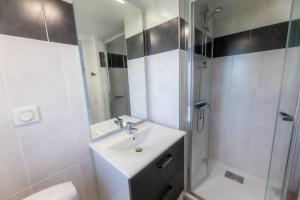 a white bathroom with a sink and a shower at Sphinx Résidences - Les Doges / Le Rialto in Caen