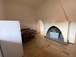 a kitchen with a fireplace and a table and a refrigerator at Casale Colle dei Pini - Rooms in Casaccia