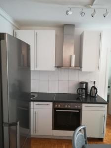 cocina con armarios blancos y fogones negros en Apartment Froschkönig, en Gladenbach