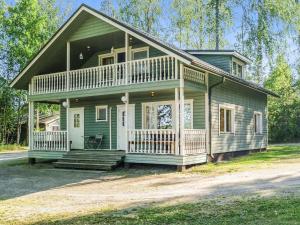 a small green house with a porch and a balcony at Holiday Home Kesäranta by Interhome in Simanala