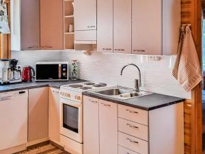 a kitchen with white cabinets and a sink at Holiday Home Kesäranta by Interhome in Simanala +17 photos