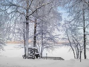 a snow covered park with a bench and trees at Holiday Home Kesäranta by Interhome in Simanala