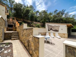 un patio con pared de piedra, mesa y sillas en Villa Cala Santanyí Beach House JM by Interhome, en Santanyí