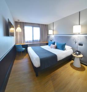 a hotel room with a large bed with blue pillows at Hôtel Le Roosevelt Lyon in Lyon