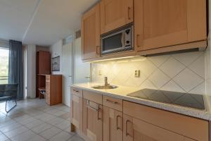 eine Küche mit einer Spüle und einer Mikrowelle in der Unterkunft Wijde Blick appartement 208 - Callantsoog in Callantsoog