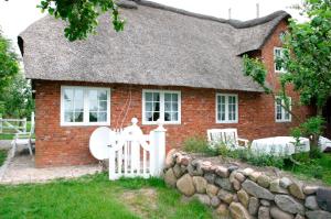 a brick house with a thatched roof and a white gate at Friesenhof Mühlenwarft in Dagebüll