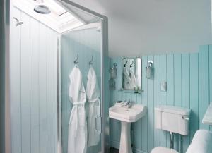 a blue bathroom with a shower and a sink at The Swan Hotel in Southwold
