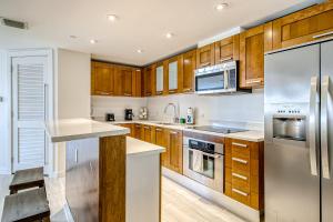 a kitchen with wooden cabinets and stainless steel appliances at Modern Ocean Drive Condo in the Heart of Sobe! in Miami Beach