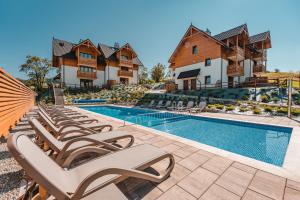 a row of lounge chairs next to a swimming pool at Ostoja Zaskalskie Apartament Rubin 52 metry in Jaworki