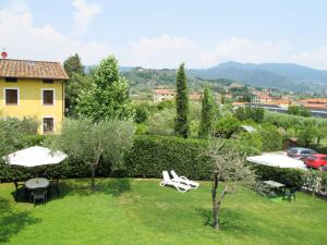 a view of a garden with chairs and umbrellas at Apartment Le Fornaci-6 by Interhome in San Quirico di Moriano