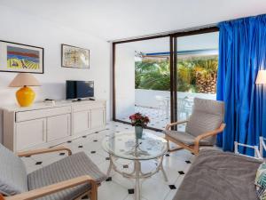 een woonkamer met een tafel en stoelen en een televisie bij Apartment Ducado Golf CII by Interhome in Pals