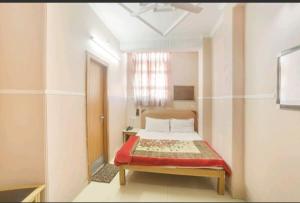 una camera con un letto con una coperta rossa di Hotel Queen a Haridwār