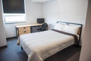 a bedroom with a bed and a desk with a computer at Residence & Conference Centre - North Bay in North Bay