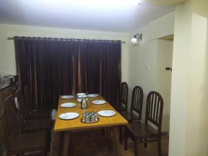 uma mesa de jantar com cadeiras e uma mesa de madeira sidx sidx sidx em Heritage Holiday Home em Ooty