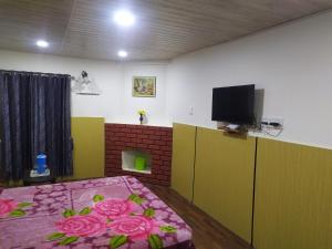 a room with a bed and a flat screen tv at Heritage Holiday Home in Ooty