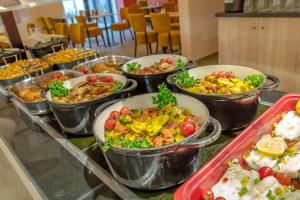 a buffet filled with different types of food in metal containers at SOWELL RESIDENCES Chênes Verts in Saint-Raphaël