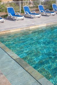 a swimming pool with blue lounge chairs and a swimming pool at SOWELL RESIDENCES Chênes Verts in Saint-Raphaël