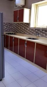 a kitchen with red cabinets and a black refrigerator at Marina Arar Furnished Apartments in Arar