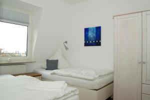 een witte kamer met 2 bedden en een raam bij Hellinghaus FeWo 3 Strandläufer in Wyk auf Föhr