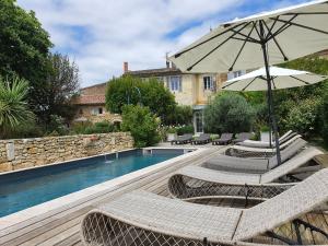 a swimming pool with two chairs and an umbrella at Le Clos Réaud in Blaye