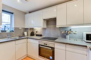 een keuken met witte kasten, een spoelbak en een magnetron bij GF flat sleeps 4, parking for Contractors by Eagle Owl Stays in Crawley +7 foto's