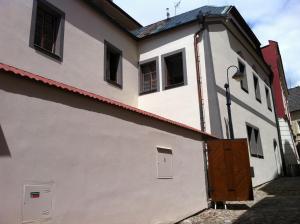 a white building with a wooden door next to a street at Penzion THIR in Tábor