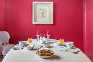 a dining room with a table with a pink wall at Les Glycines in Croix