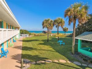 un patio con sillas, palmeras y el océano en South Beach Inn - Cocoa Beach, en Cocoa Beach