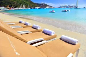 a row of chaise lounge chairs on a beach at Holland House Beach Hotel in Philipsburg
