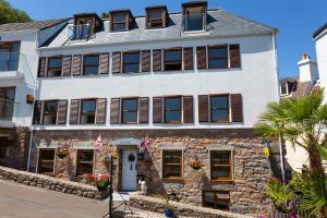 a large white building with brown shuttered windows at Porthole Suites in Saint Aubin