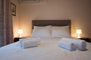 a white bed with two pillows on it with two lamps at Rodami in Kaléntzion