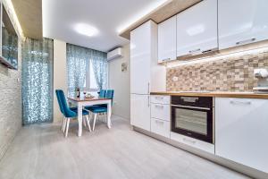 a kitchen with white cabinets and a table and chairs at Апартамент S Apart in Varna City