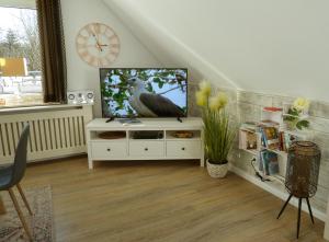 a living room with a television on a white cabinet at Villa am Deich in Westerdeichstrich