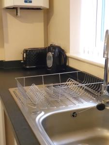 a kitchen sink with a drying rack next to a microwave at Lt Properties Luton town centre studio Tv Netflix Ground Floor 2 in Luton