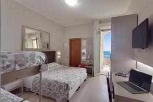 Schlafzimmer mit einem Bett und einem Schreibtisch mit einem Laptop in der Unterkunft Hotel San Giorgio in Cesenatico