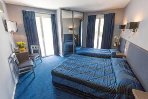 una camera d'albergo con due letti e una televisione di Hôtel Irlande a Lourdes