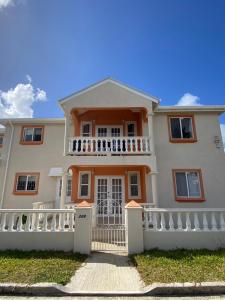 une grande maison blanche avec une clôture blanche dans l'établissement Ixoras Beach Apartments, à Saint Peter