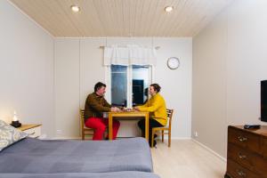 two people sitting at a table in a bedroom at Labbnäs Semesterhem, Radhuset in Kemionsaari