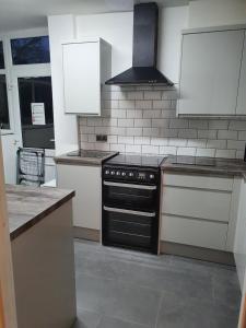 a kitchen with a black stove and white cabinets at Central Location Preston 1 in Preston
