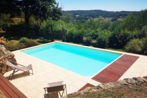 a swimming pool in a yard with two chairs at Dans la bastide de Domme - piscine chauffée, parking privé in Domme