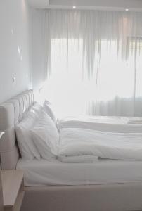 uma cama branca com almofadas brancas e uma janela em Apartment Ori em Drama