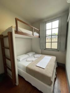 a bedroom with two bunk beds and a window at Casarão Hostel in Capitólio