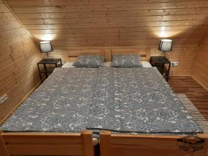 Cama grande en habitación de madera con 2 lámparas en Domki Wisła Dolina Partecznik, en Wisła