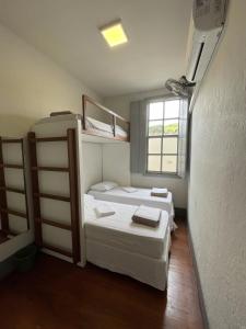 a room with three bunk beds and a window at Casarão Hostel in Capitólio