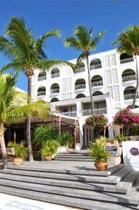 a white building with palm trees in front of it at Holland House Beach Hotel in Philipsburg