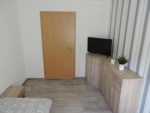 a room with a door and a television on a dresser at sommer-zimmervermietung in Magdeburg