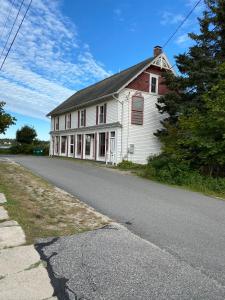 uma velha casa branca na beira de uma estrada em Harbor House Hotel by Umaniii in Jonesport Maine em Jonesport