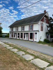 una casa blanca con adornos rojos en una calle en Harbor House Hotel by Umaniii in Jonesport Maine en Jonesport